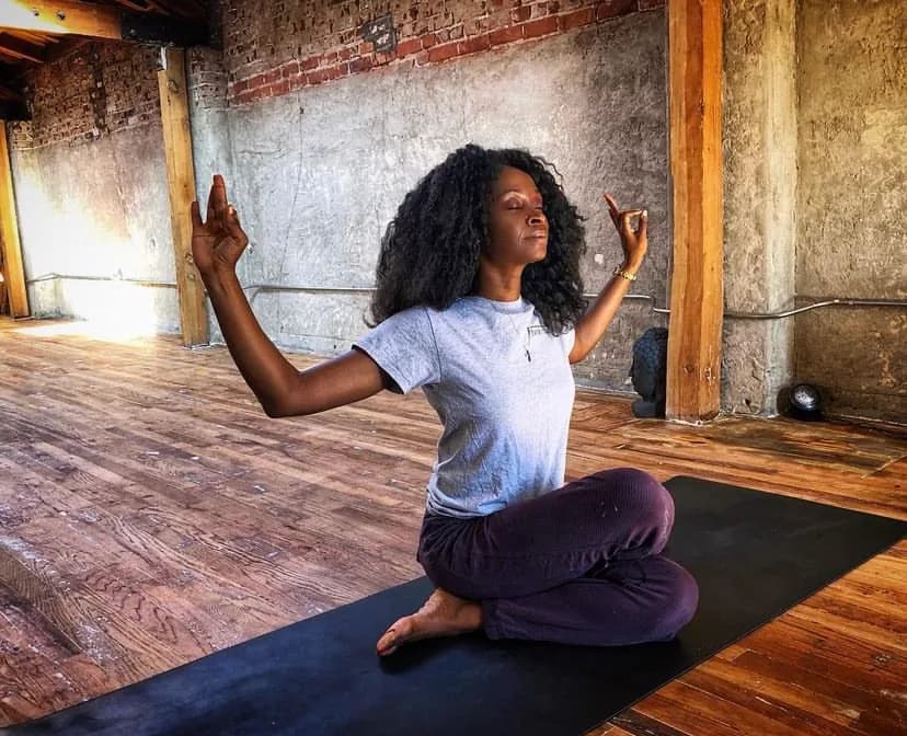 Chioma Sutton, founder and yoga teacher at Radha Yoga LA, practicing seated yoga in a Los Angeles studio
